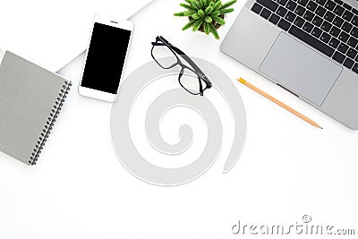 Creative flat lay photo of workspace desk. Top view office desk with laptop, glasses, phone, pencil, notebook and plant on white Stock Photo