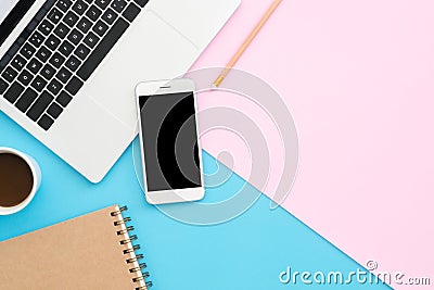 Top view office desk with laptop, phone, pencil, notebook and coffee cup on blue pink color background. Stock Photo