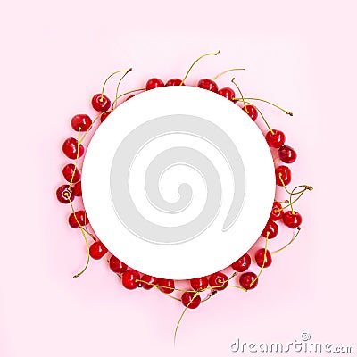 Creative circle frame of red ripe cherries with green mint leaves on a pink background. View from above. Flat lay Stock Photo