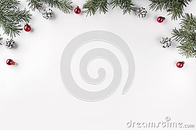 Creative frame made of Christmas fir branches on white background with red decoration, pine cones. Stock Photo