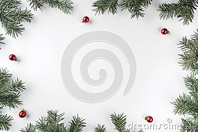 Creative frame made of Christmas fir branches on white background with red decoration, pine cones. Stock Photo