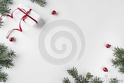Creative frame made of Christmas fir branches on white wooden background with red decoration, pine cones Stock Photo