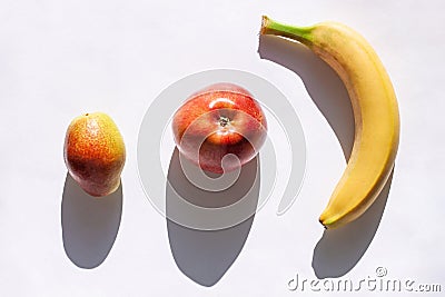 Creative healthy breakfast concept on a white background flat lay. Fresh banana, apple, pear fruits with natural shadow Stock Photo