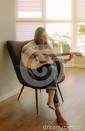 Creative hobby. Talented young female musician sit in armchair alone compose instrumental song using classic guitar. Copy space Stock Photo