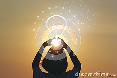 Creative idea and innovation concept, Woman hand holding light bulb on beautiful sunset background Stock Photo