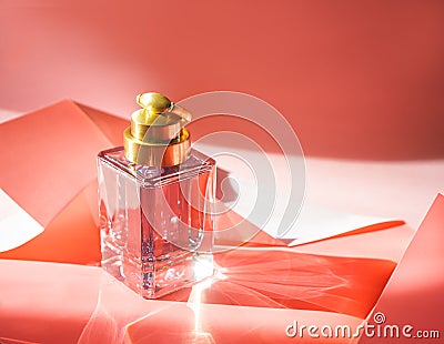 Creative layout made of perfume in beautiful pink bottle on folded paper of living coral color. Minimal style of beauty and Stock Photo