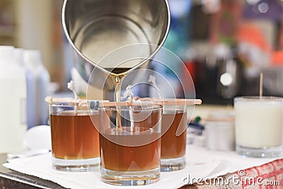 Creative occupation of candle making showing the pouring of liquid wax into jars Stock Photo