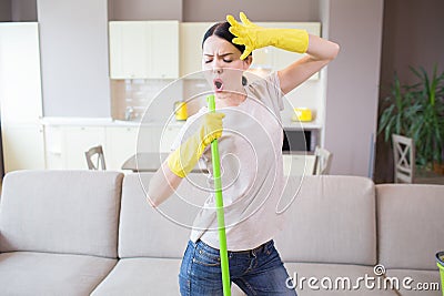 Creative person stands. She is singing and dancing. Girl holds left hand on forehead. Woman has green stick in right Stock Photo