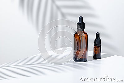 Creative photo of cosmetic bottle with pipette on a white background with shadow of tropical flower Stock Photo