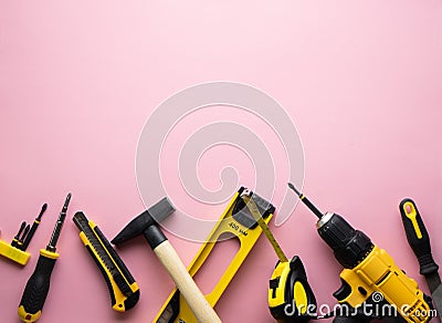 Creative provocation: a flat layout of yellow hand tools on a pink background. Stock Photo
