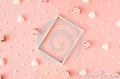 Creative romantic layout made of white frame, hearts and roses on pastel pink background. Stock Photo