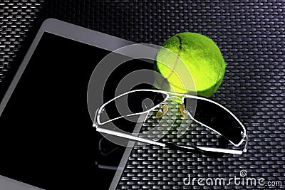 Creative Set Tennis ball, tablet computer and black sunglasses, close-up, on metal background. Stock Photo