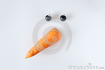 Creative snowman face made of carrots and black Christmas balls on a white background. Stock Photo