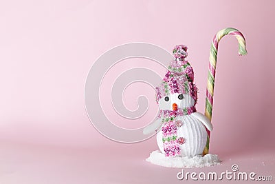 Creative snowman with sweet candy cane on a pink background Stock Photo