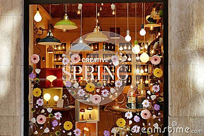 Creative Spring claim lettering and floral composition on lamps and lightbulbs design shop window Editorial Stock Photo