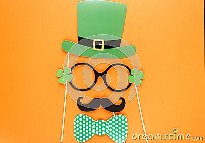 Creative st Patricks Day orange background. Flat lay composition of Irish holiday celebration with photo booth decor: hat, glasses Stock Photo