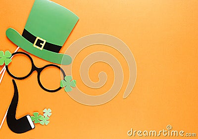 Creative st Patricks Day orange background. Flat lay composition of Irish holiday celebration with photo booth decor: hat, glasses Stock Photo