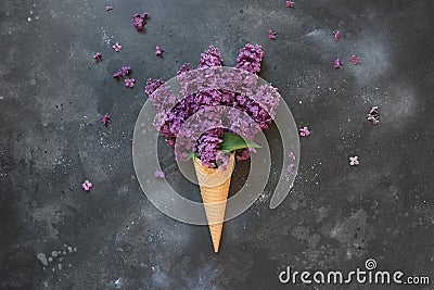 Creative still life of pink lilac in waffle ice cream cone on vintage black table. Spring. Top view Stock Photo