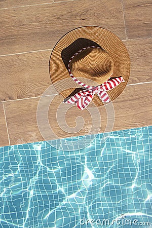 Creative Summer pool concept of a lady straw hat next to the water. Sunny party day, flat lay Stock Photo