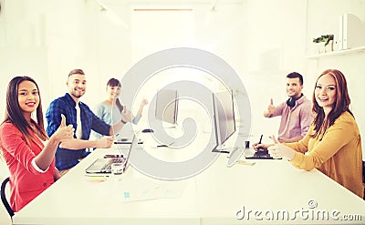 Creative team with computers showing thumbs up Stock Photo