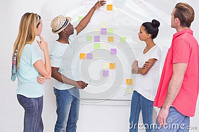 Creative team looking at sticky notes on wall Stock Photo