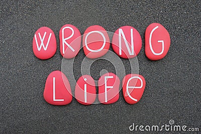 Wrong life text composed with red colored stone letters over volcanic sand Stock Photo