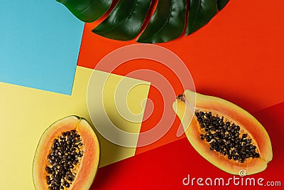 Creative tropical layout with papaya and palm tree leaves on colorful vivid paper. Minimal abstract summer concept. Flat lay Stock Photo