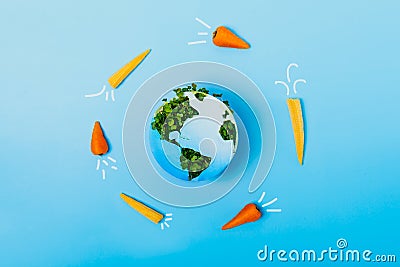 Creative veganism and Earth day concept. Rockets of carrots and baby corn flying around planet Earth. Earth model made Stock Photo