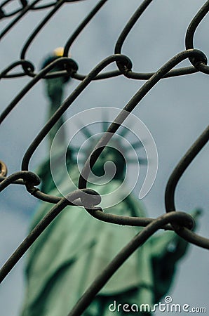 Creative vertical shot of the Statue of Liberty through a gate located in New York, US Stock Photo