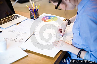 Creative woman fashion designer in glasses sitting and drawing sketches Stock Photo