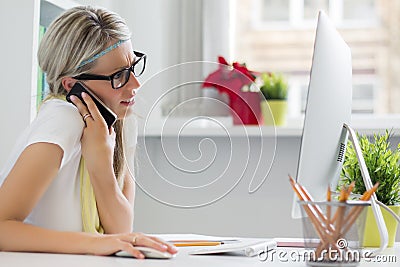 Creative woman talking on phone in the office Stock Photo