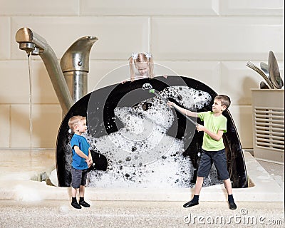 Creative work: three miniature children wash a large black plate with foam. Homework concept Stock Photo