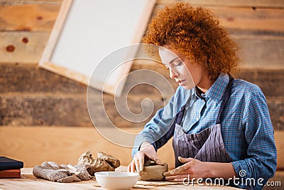 Creative young woman potter making earthen dishes in workshop Stock Photo