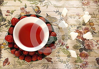 Creatively served fruit tea and strawberries on saucer Stock Photo