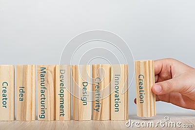 Creativity concept. Hand places the wooden rectangles next to the others, creating a wall of wooden cubes with the words Stock Photo