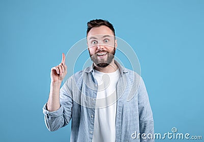 Creativity, idea, inspiration. Cool guy pointing finger up, gesturing eureka, experiencing AHA moment on blue background Stock Photo