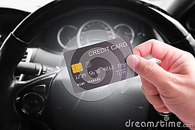 Credit cards and financial privileges concept, hand holding luxury credit or debit card with a steering wheel background in a car Stock Photo