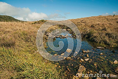 Creek going through hills covered by dry bushes Stock Photo