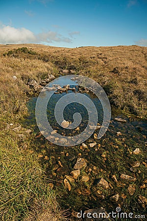 Creek going through hills covered by dry bushes Stock Photo