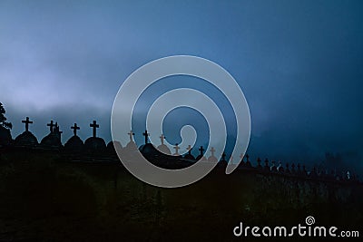 Creepy spooky graveyard atmosphere in the cemetery with tombstone and crosses in the foggy night Stock Photo