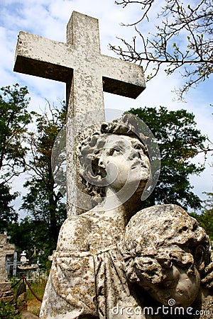 Creepy stone cross with statue in the cemetery Stock Photo