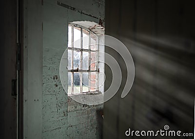 creepy wooden cellar window in abandoned workhouse viewed through open door bright sun light rays Stock Photo