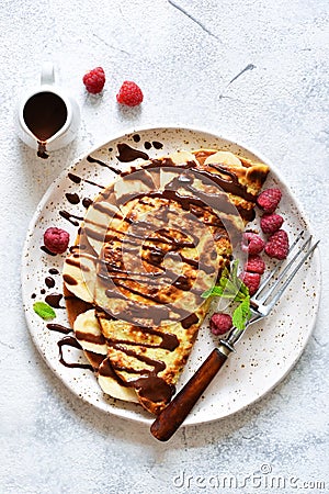 Crepe with chocolate paste, banana and raspberries on a concrete background. Tasty breakfast Stock Photo