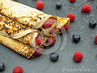 Crepes filled with jam and fresh raspberry and blueberries on slate Stock Photo