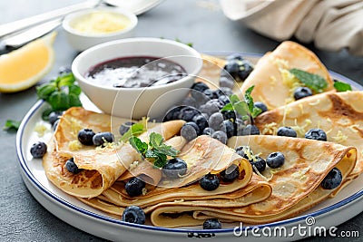 Crepes, thin pancakes with blueberry jam and fresh berries with lemon zest Stock Photo