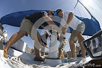 Crew Members Operating Windlass On Yacht Stock Photo
