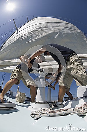 Crew Members Operating Windlass On Yacht Stock Photo