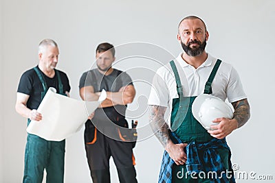 Three professional builder wearing overalls standing in empty interior Stock Photo