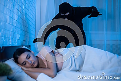 Thief ready to attack woman who is sleeping in bed Stock Photo