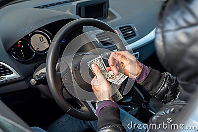 criminal man holding a large sum of dollar bills inside the car. Stock Photo